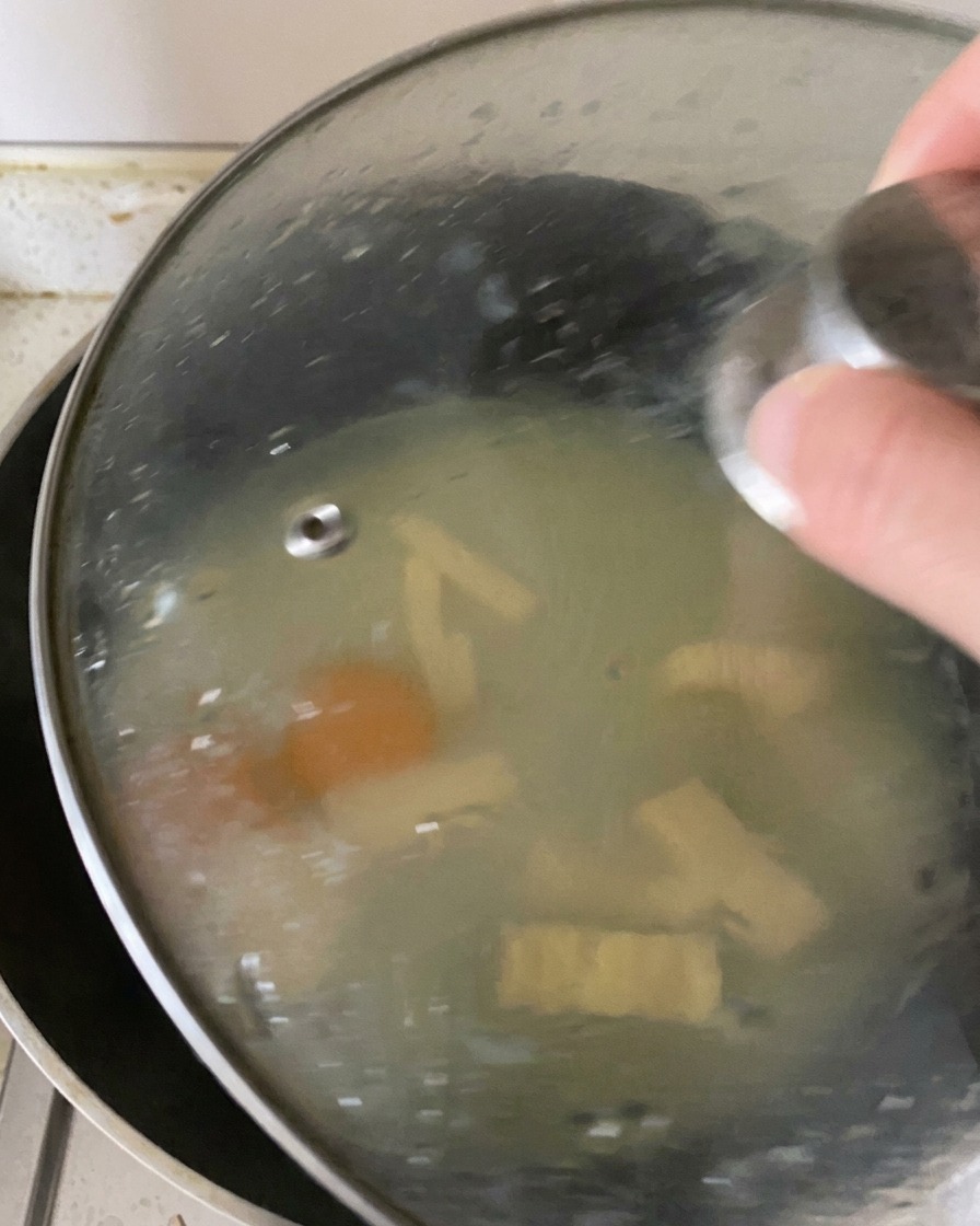 Ein Glasdeckel auf einer Bratpfanne fängt den Dampf ein, um die Eier zu garen und den Käse zu schmelzen.