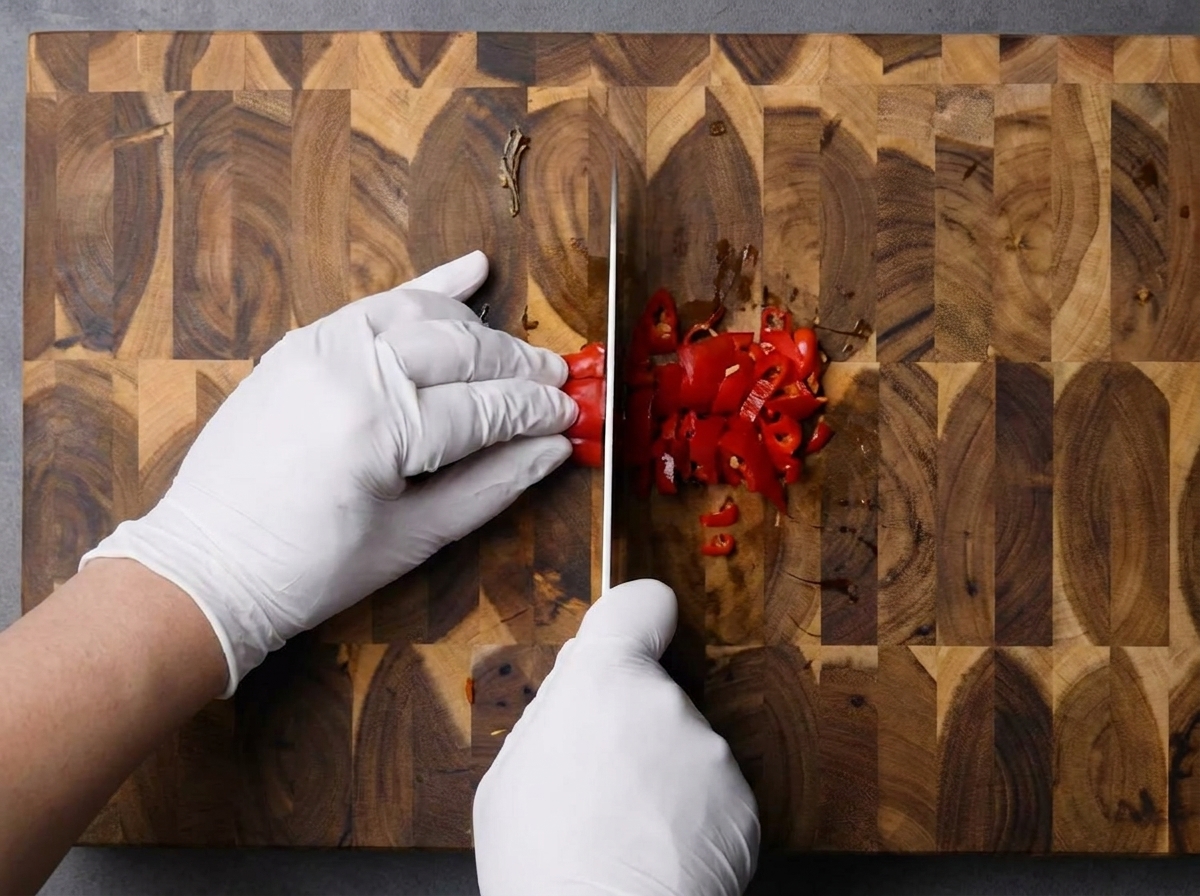 Frische rote Chilischoten werden fein gehackt auf einem Holzbrett.