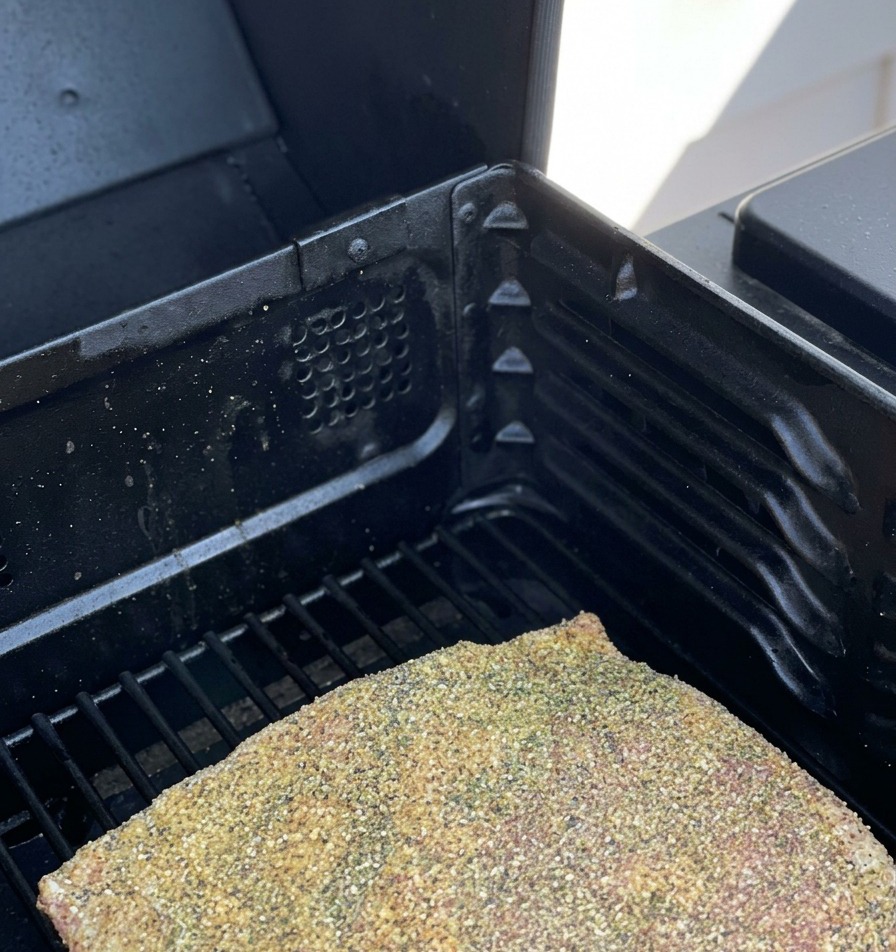 Gewürzte rohe Rinderrippen liegen auf dem Rost eines Smokers.