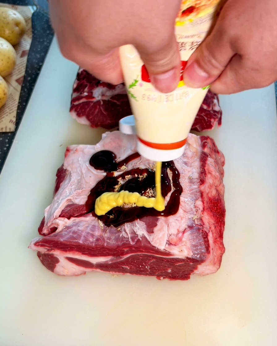 Gelber Senf wird aus einer Tube über die dunkle Austernsauce auf dem rohen Rindfleisch gedrückt.