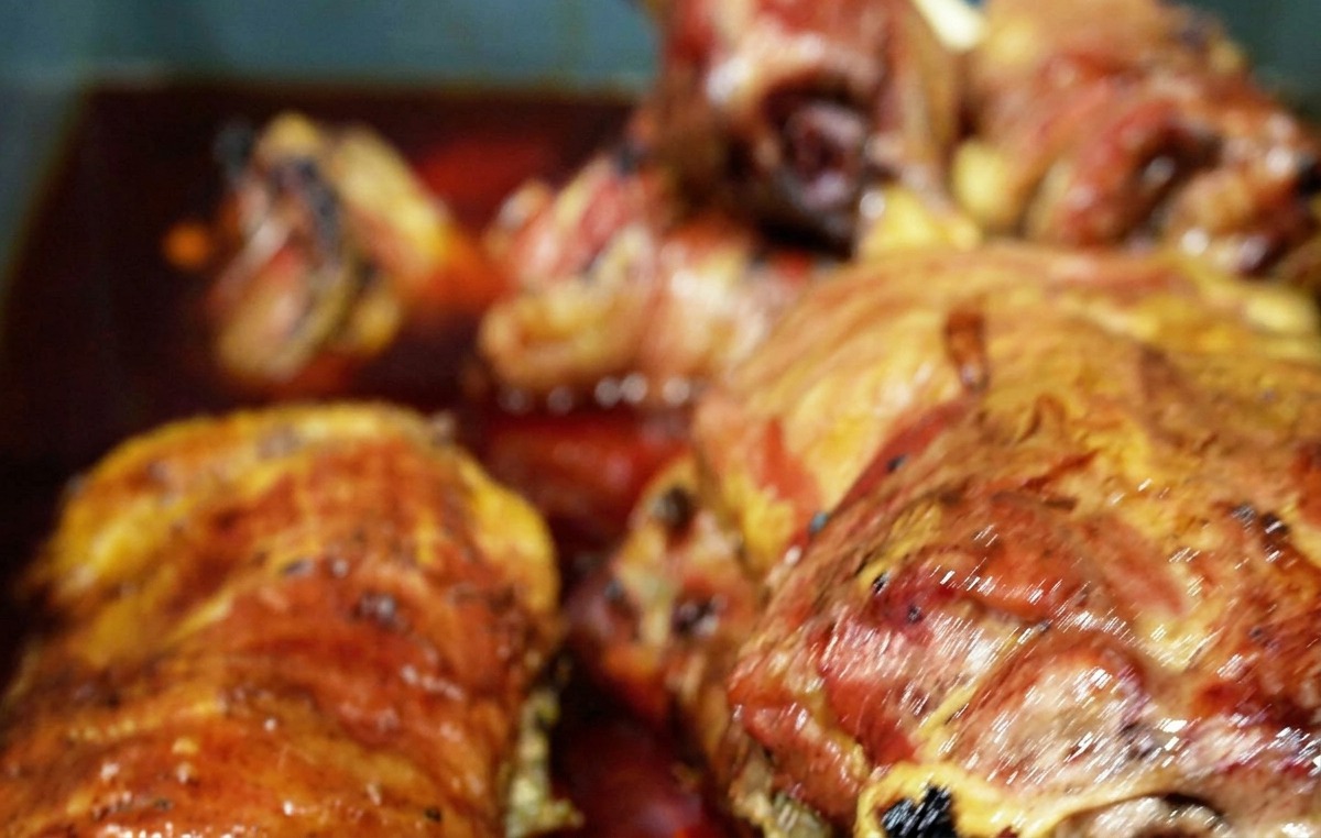 Mehrere Stücke geräuchertes Rindfleisch liegen in einer tiefen, rötlich-braunen Marinade in einer blauen Wanne.
