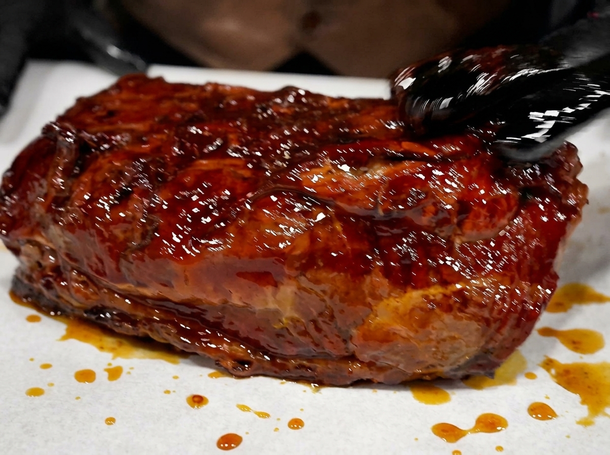 Ein Stück geräuchertes Fleisch, glänzend von der Marinade, liegt auf einer Folie bereit zum Einwickeln.