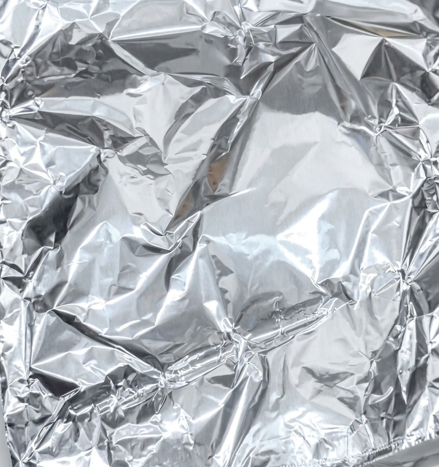 Nahaufnahme, wie Alufolie über dem Fleisch gefaltet und fest versiegelt wird.