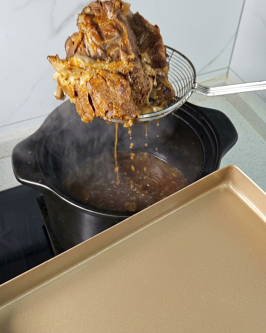 Ein Stück zartes Fleisch wird mit einem Schaumlöffel aus dem dampfenden Topf gehoben.