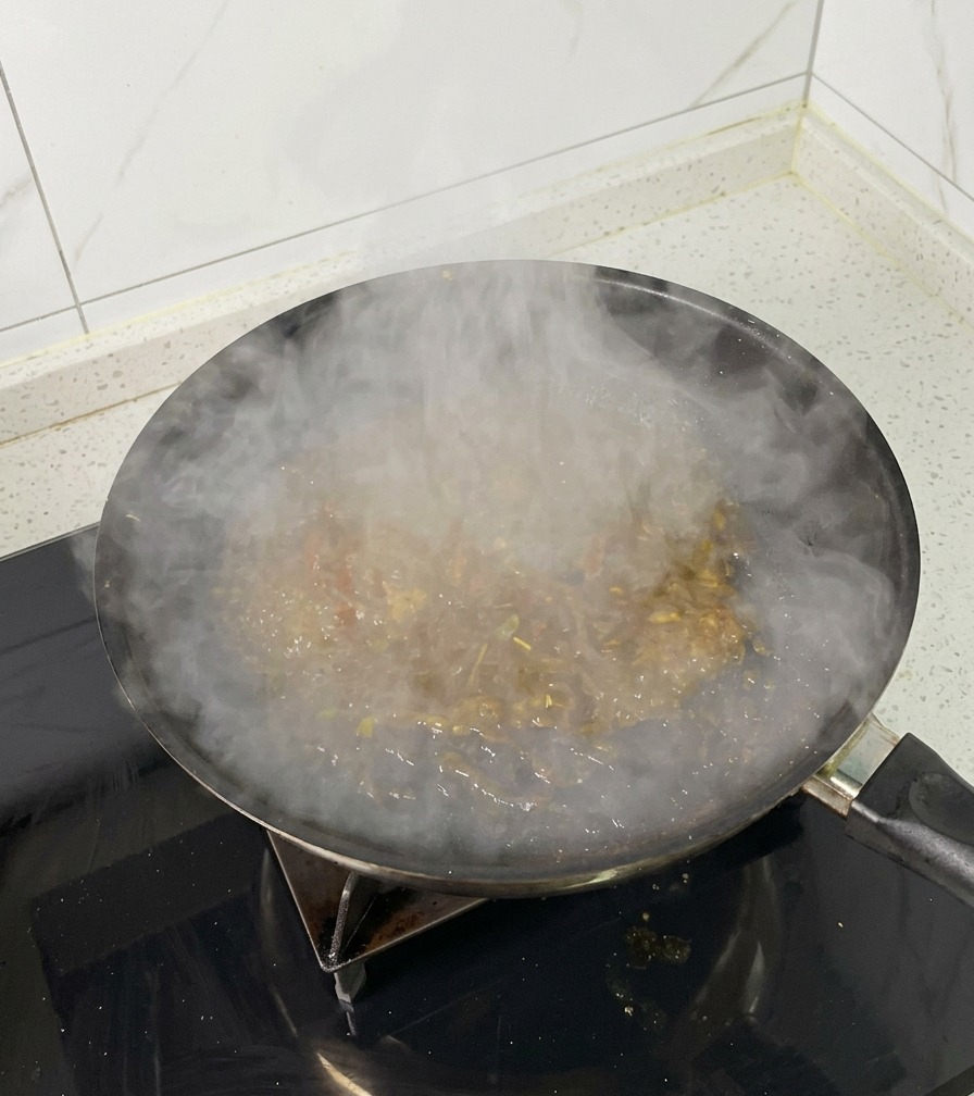 Eine Pfanne auf dem Herd mit kochender Schmorflüssigkeit, die stark dampft.