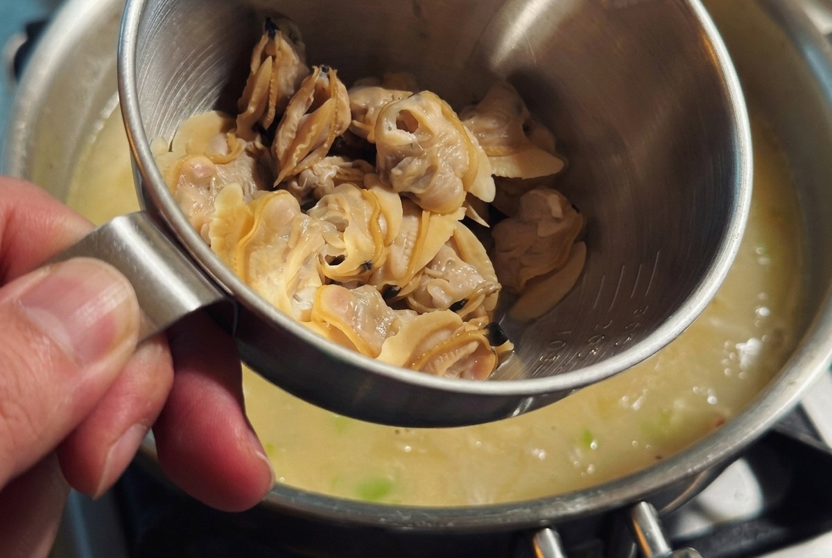 Sahne wird in den Topf gegossen und das Muschelfleisch vorsichtig untergehoben.