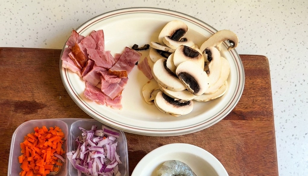 Ein weißer Teller mit in Scheiben geschnittenen weißen Champignons und Speckstücken.