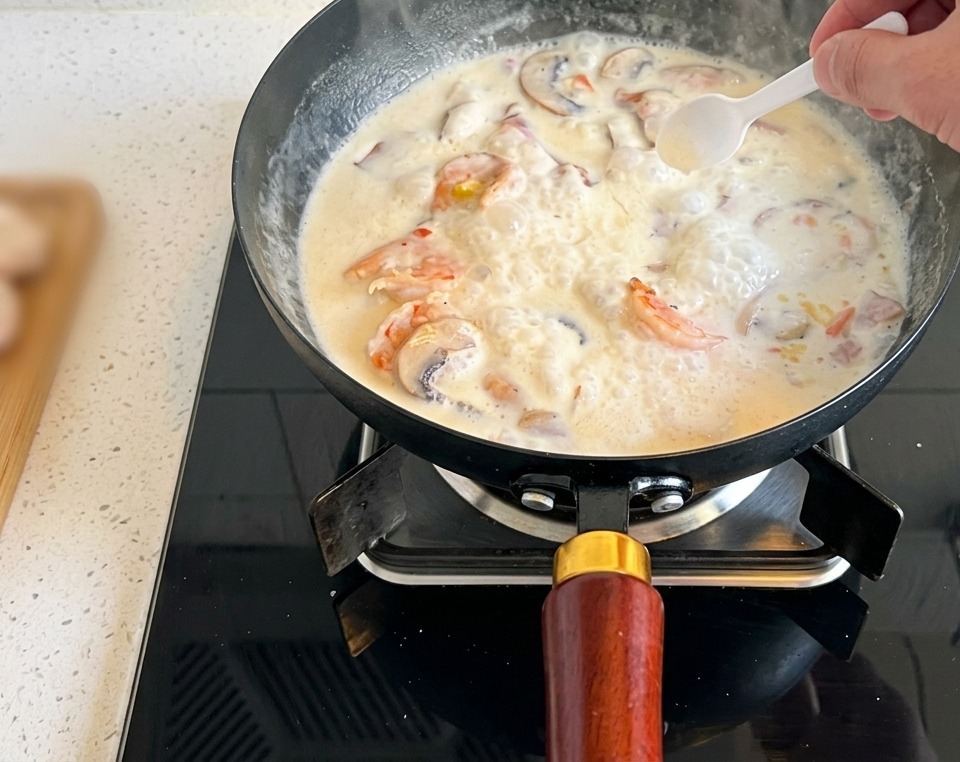 Ein kleiner weißer Löffel gibt eine Prise Salz in die kochende Pilzcremesuppe.
