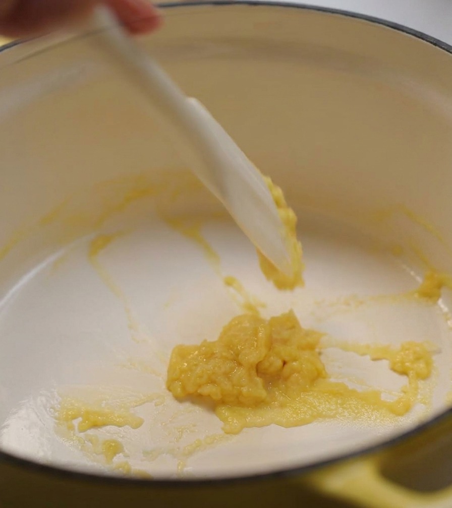 Ein Silikonspatel rührt eine dicke, blassgelbe Butter-Mehl-Paste in einem Topf.