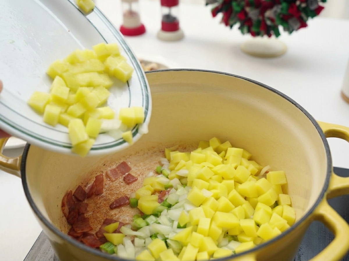 Gewürfelte Kartoffeln, Sellerie und Zwiebeln werden in einen Topf mit gebratenem Speck gegeben.
