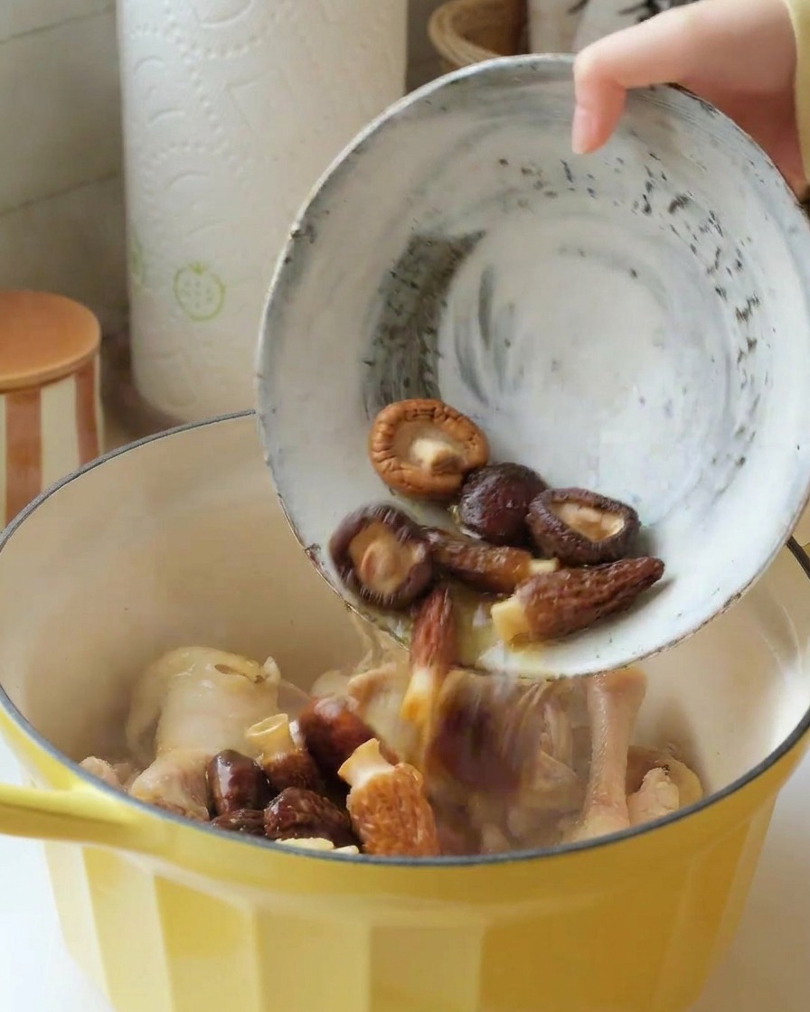 Eingeweichte Shiitake und Morcheln werden zusammen mit der Flüssigkeit in den Topf zum Hähnchen gegeben.