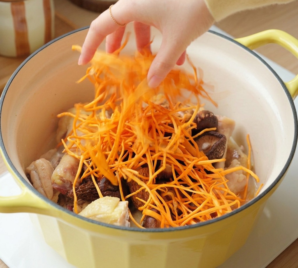 Eine Hand streut leuchtend orangefarbene Cordyceps-Blüten über Hähnchen und Pilze.