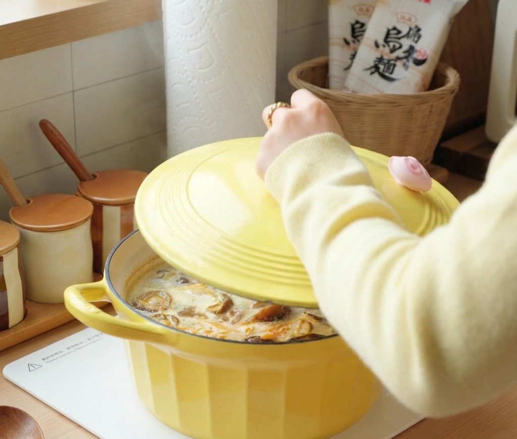 Eine Person legt den gelben Deckel auf den leicht brodelnden Topf mit der Hühnersuppe.