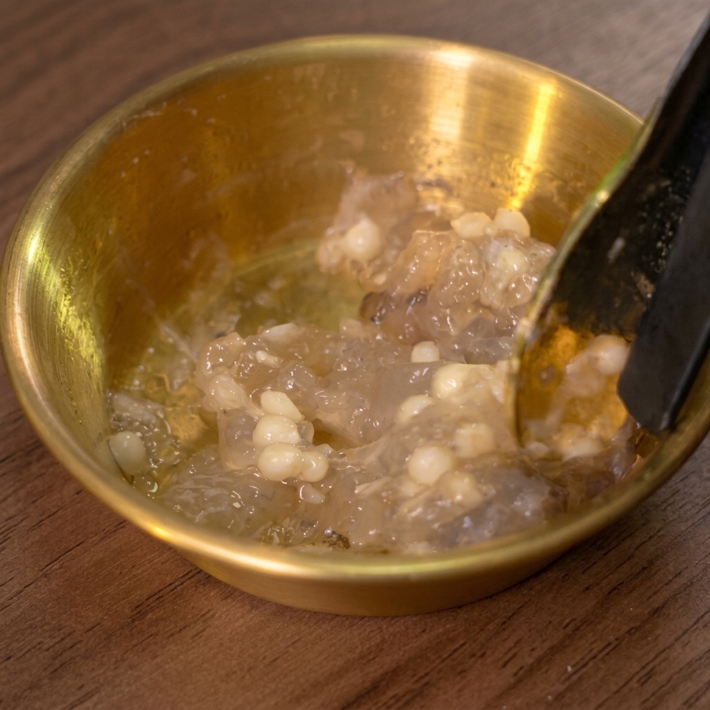 Ein Löffel rührt die Garnelenpaste in einer goldenen Schüssel an.