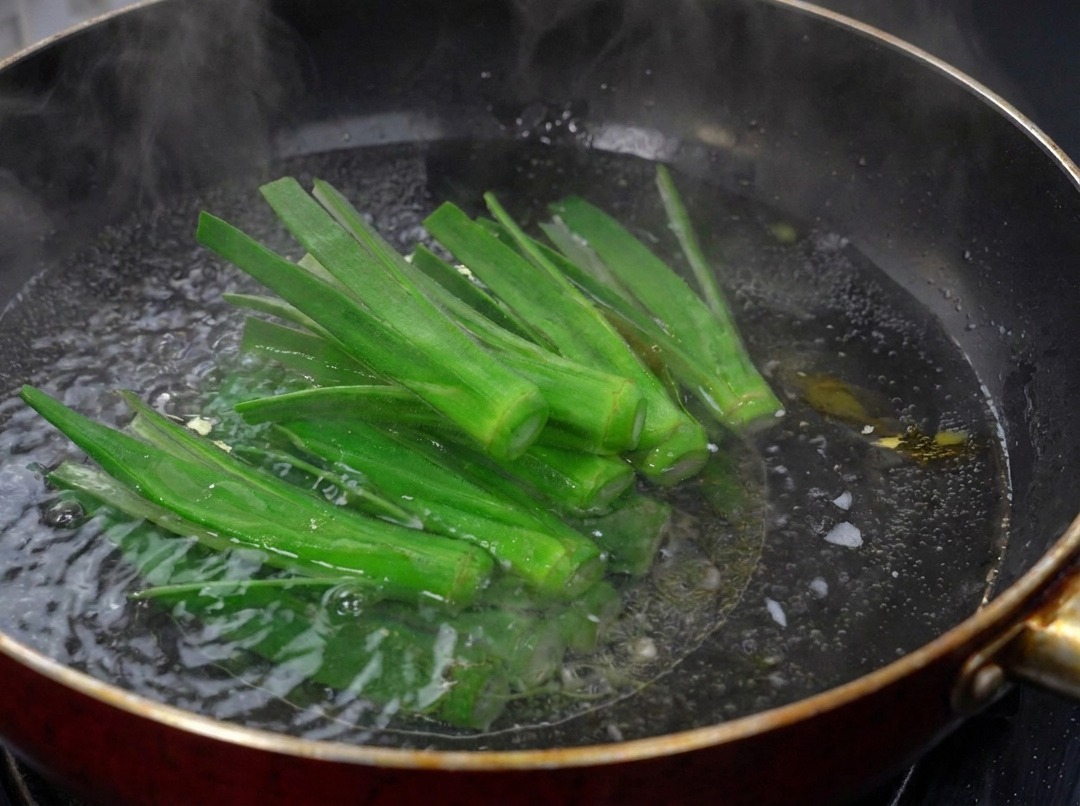 Frisch eingeschnittene grüne Okrastreifen, die in einem dunklen Wok mit sprudelnd kochendem Wasser blanchiert werden.