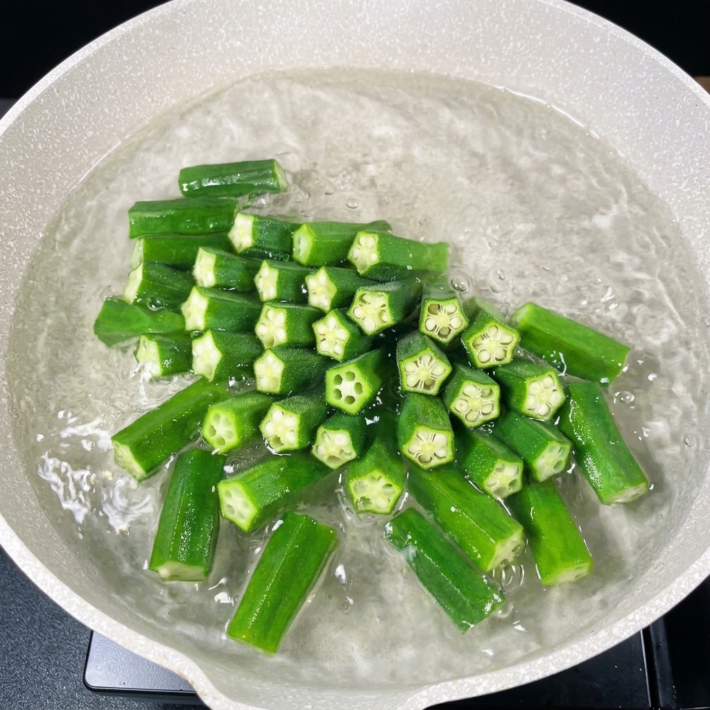 Tiefgrüne, gehackte Okrastücke kochen in einem Topf.