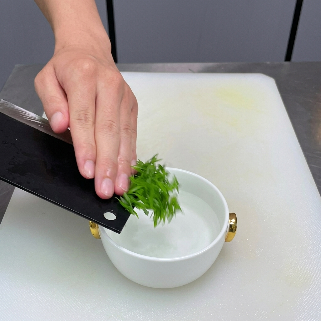 Frühlingszwiebelstreifen werden in eine kleine Schüssel mit Wasser gegeben.
