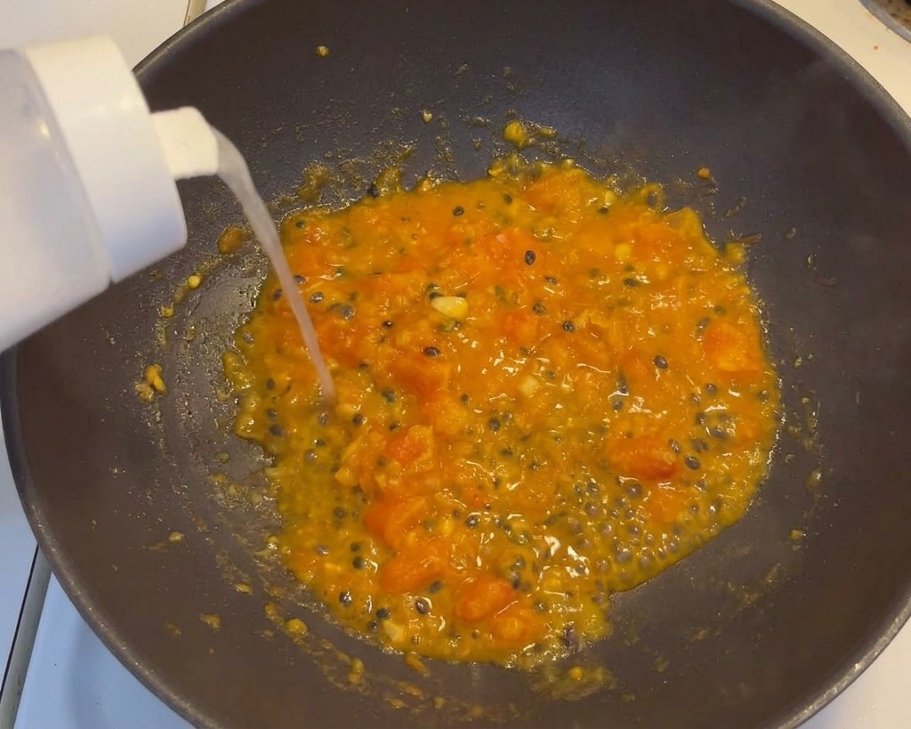 Zucker und Salz werden in die köchelnde Tomaten-Passionsfrucht-Mischung gegeben.