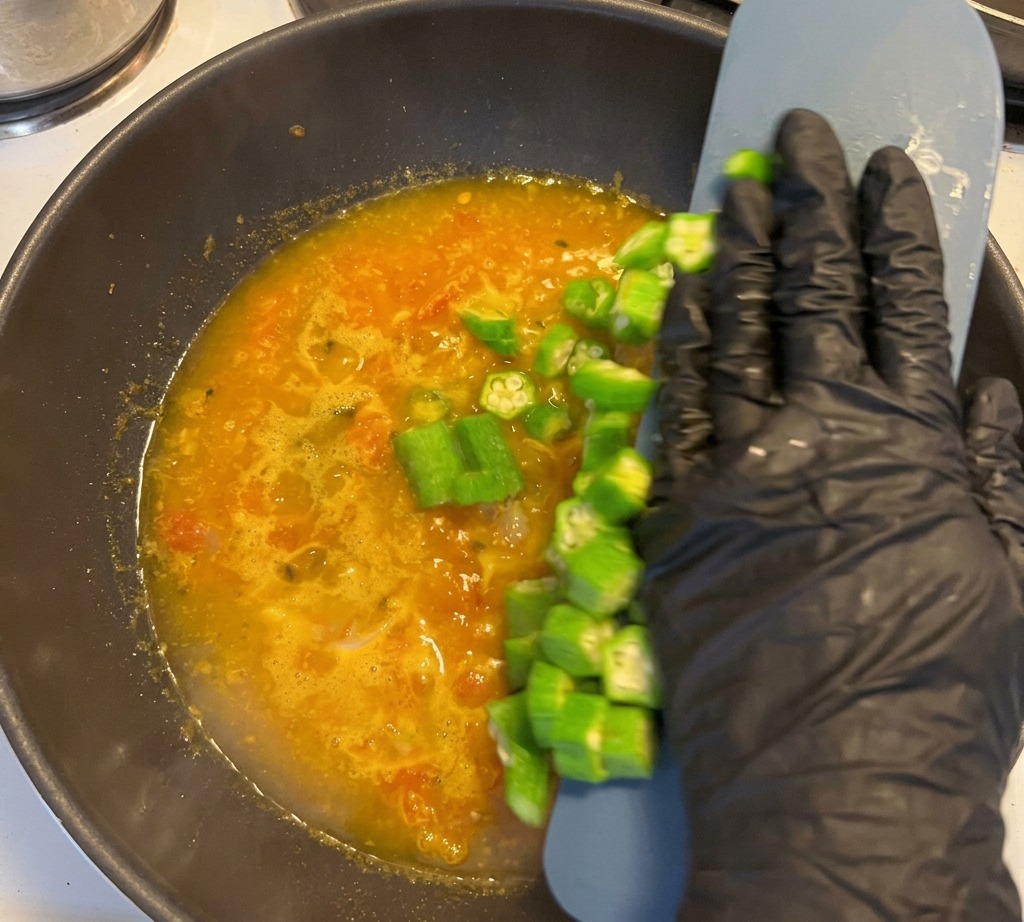 Geschnittene Okra-Sterne werden in die köchelnde Suppe gegeben.