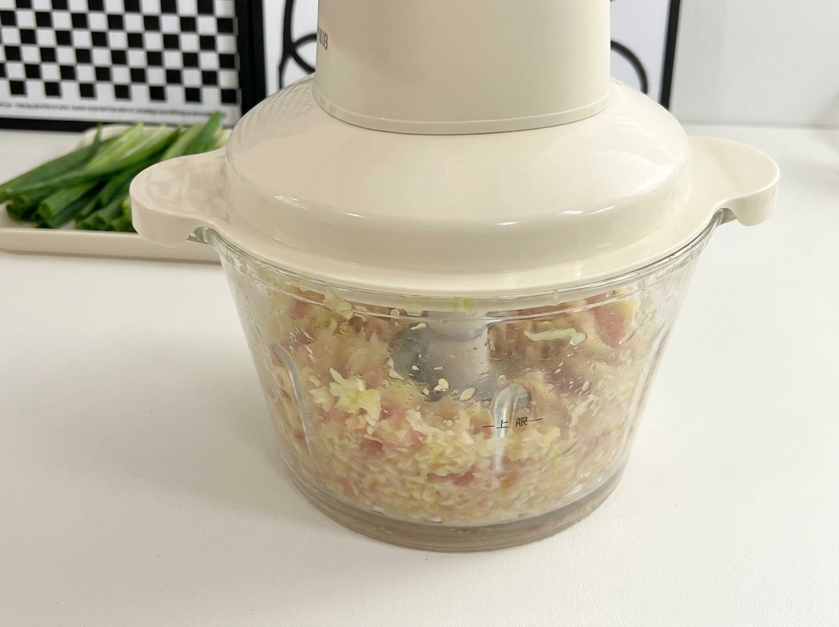 Ein kleiner Mixer verarbeitet Hähnchen und Okrakerne zu einer feinen Masse.