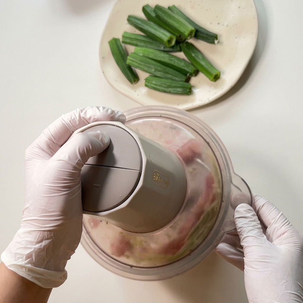 Hähnchen und Okra-Reste werden im Mini-Zerkleinerer zu einer Paste verarbeitet.