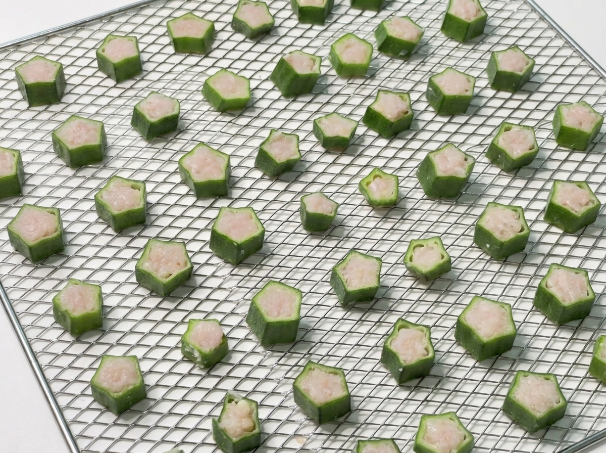 Ein voll belegtes Gitter mit Okra-Happen wird in den Dörrautomaten geschoben.