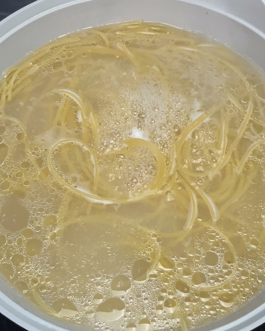 Spaghetti wirbeln in sprudelnd kochendem Wasser in einem Topf.