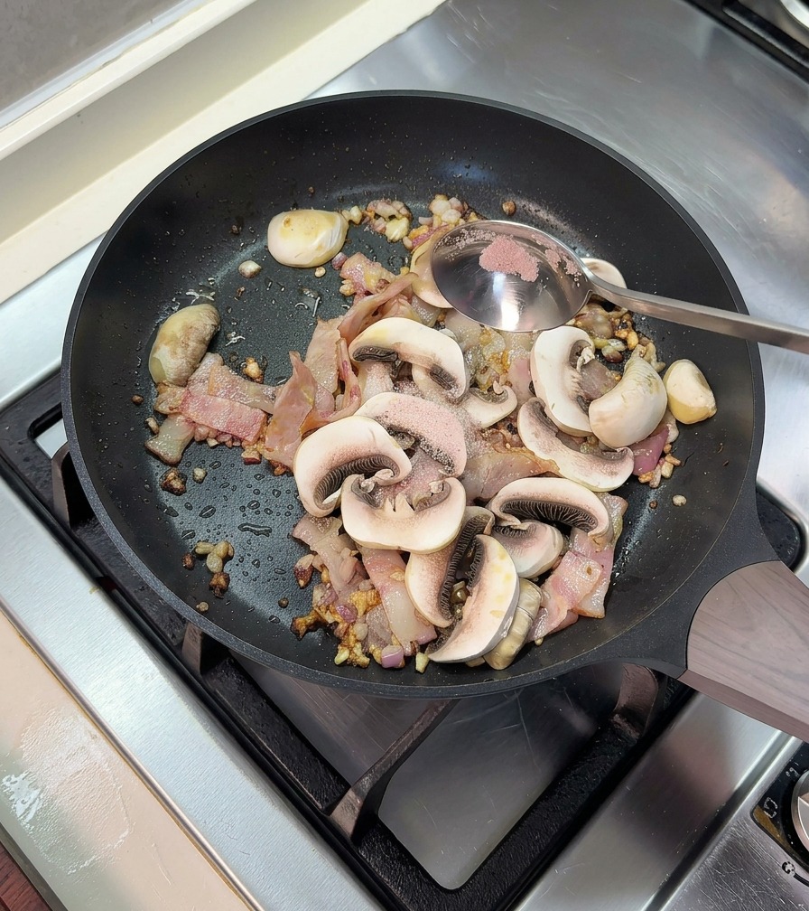 Zugabe eines Löffels rosa Salz in eine Bratpfanne mit gebratenem Speck und in Scheiben geschnittenen Champignons.