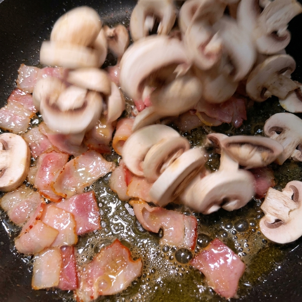 Geschnittene weiße Champignons werden in eine Pfanne zu den brutzelnden Speckstücken gegeben.