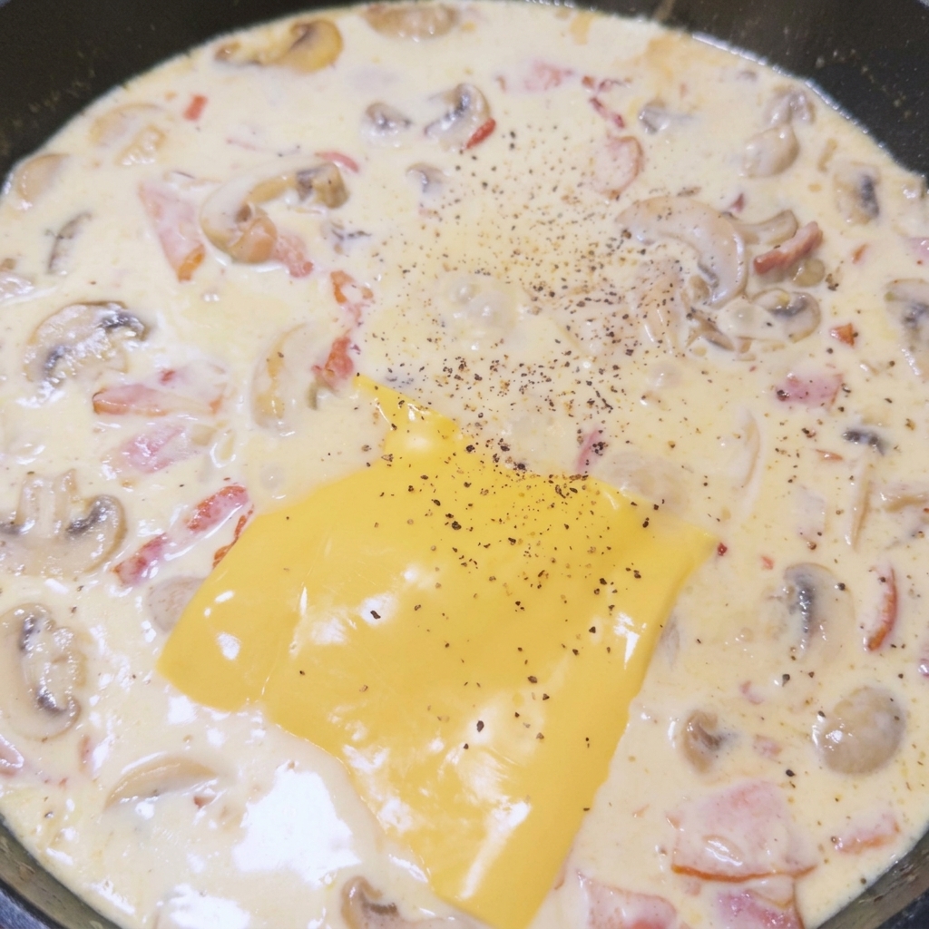 Schmelzender Käse in der Pfanne, großzügig mit frisch gemahlenem schwarzem Pfeffer bestreut.
