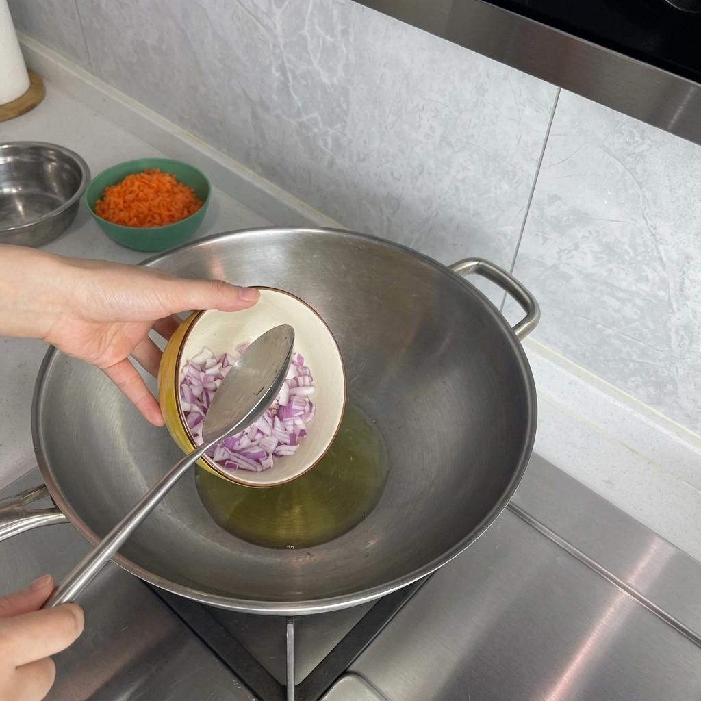 Rote Zwiebelwürfel werden aus einer kleinen Schüssel in einen Wok mit heißem Öl gegeben.