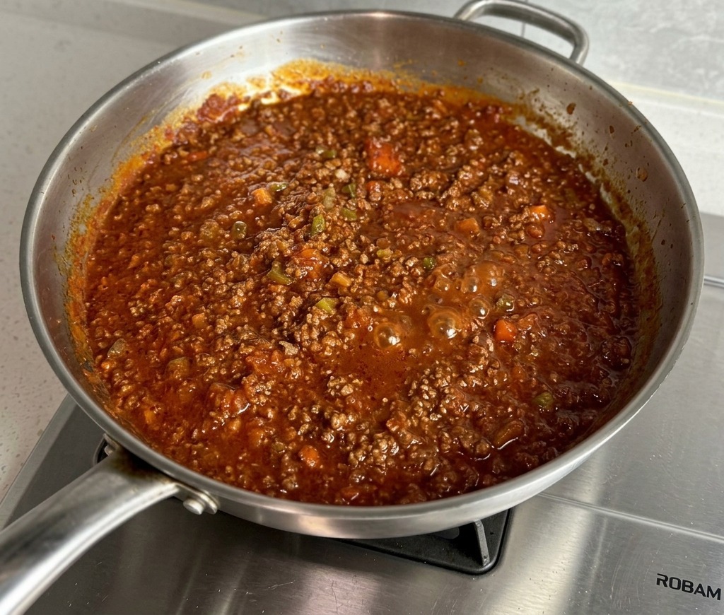 Dicke, blubbernde rote Fleischsauce köchelt in der Pfanne.