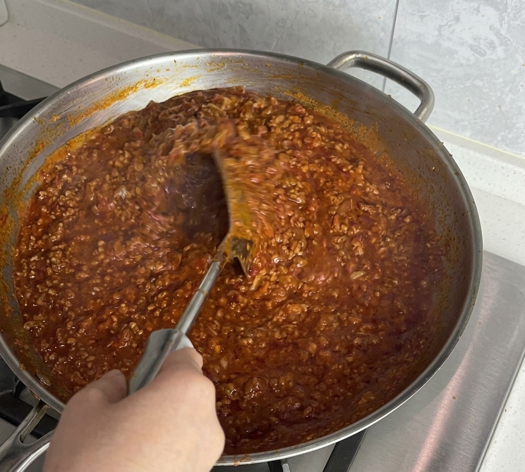 Die Sauce wird kräftig umgerührt, um die Butter einzuarbeiten.
