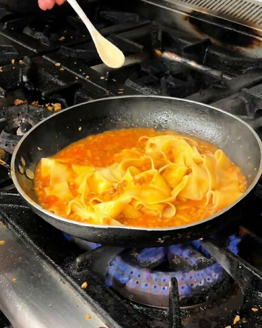 Pappardelle-Nudeln köcheln in Fleischsauce in der Pfanne.