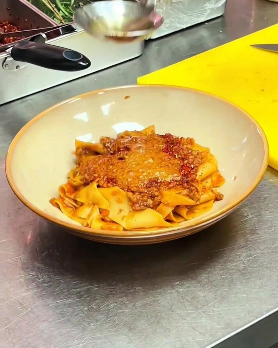 Ein pochiertes Ei wird vorsichtig auf die Mitte der Pasta mit Chili-Öl gelegt.