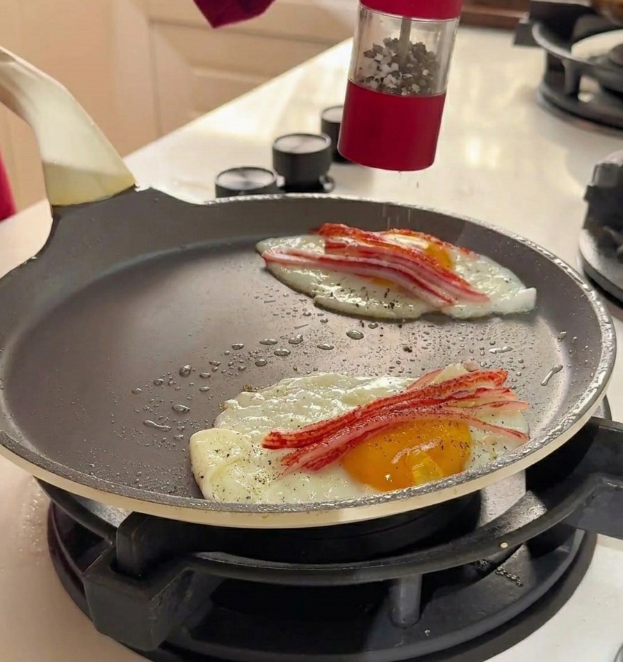 Meersalz und schwarzer Pfeffer werden mit einer roten Mühle über die Eier und das Surimi in der Pfanne gemahlen.