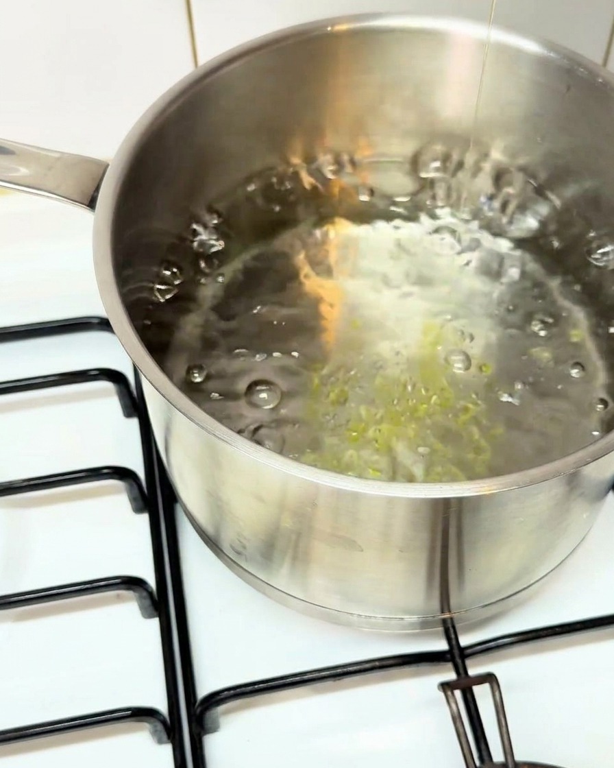 Dicke Paccheri-Pasta-Röhren werden in einen Edelstahltopf mit sprudelnd kochendem Wasser gegeben.