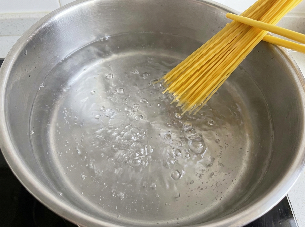 Trockene Spaghetti-Nudeln werden in einen Topf mit sprudelnd kochendem Wasser gegeben.