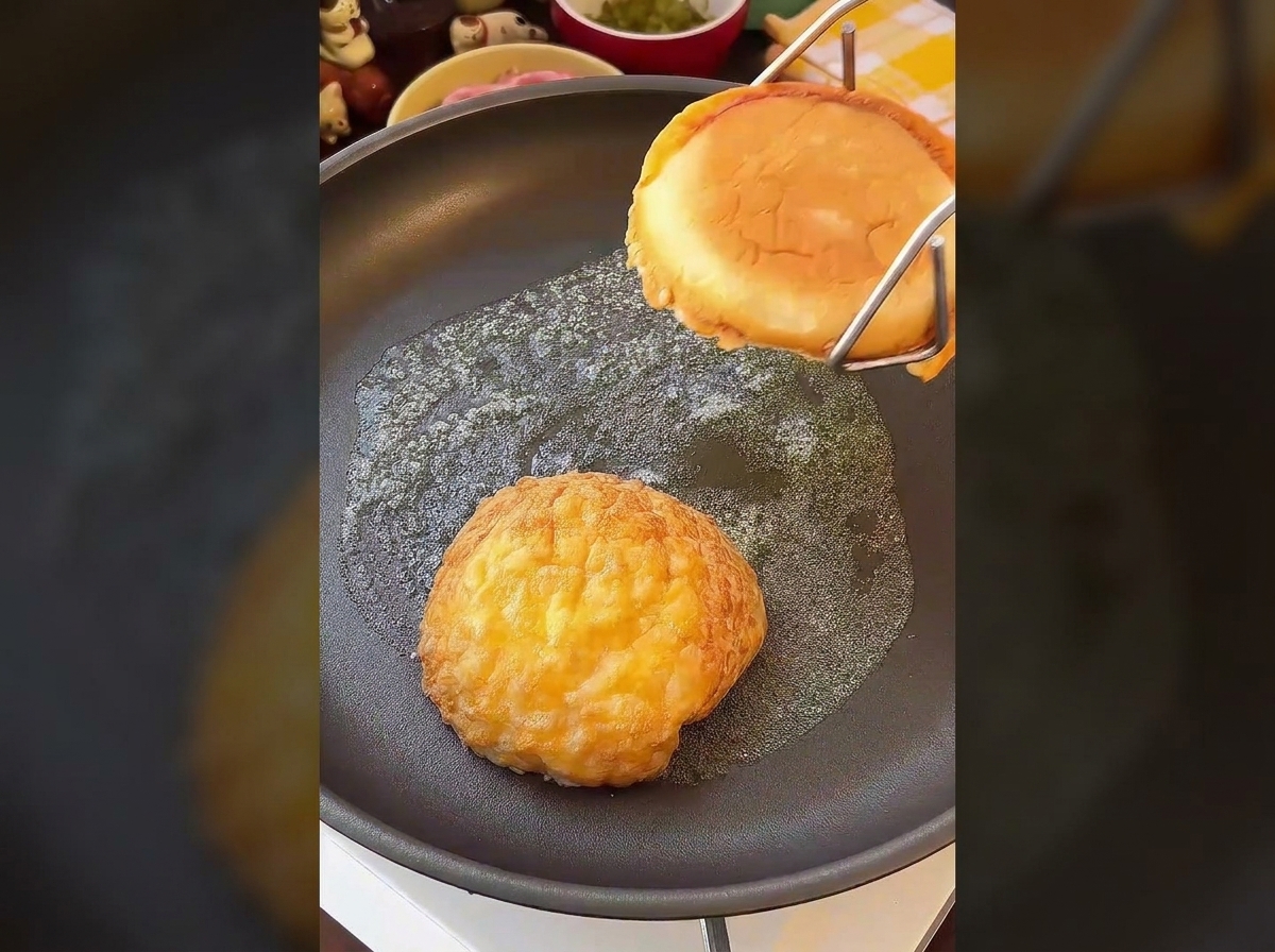 Zwei Hälften eines Burgerbrötchens werden mit der Schnittseite nach unten in Butter goldbraun geröstet.