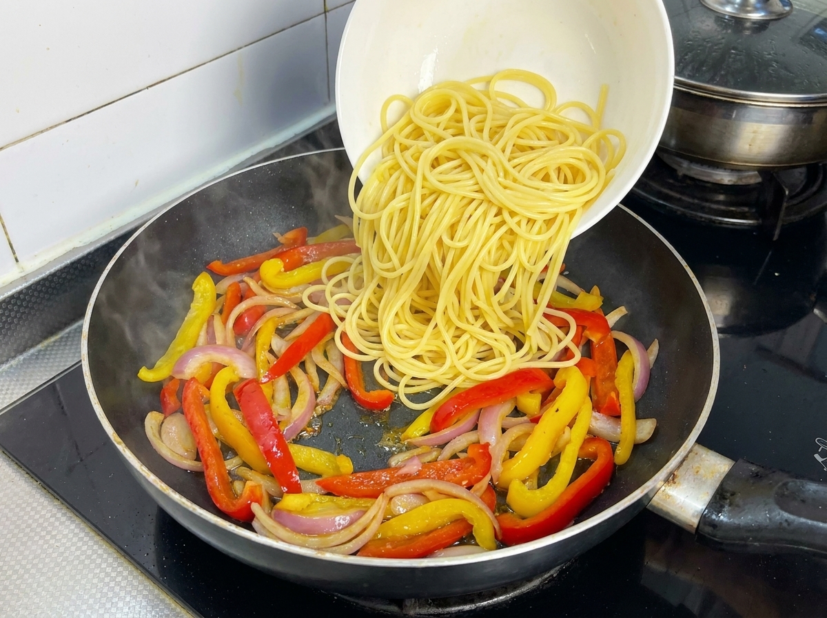 Gekochte Spaghetti werden zum Pfannengemüse gegeben.