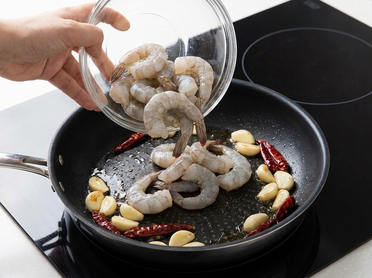 Rohe Garnelen werden in die heiße Pfanne zu Knoblauch und Chili gegeben.