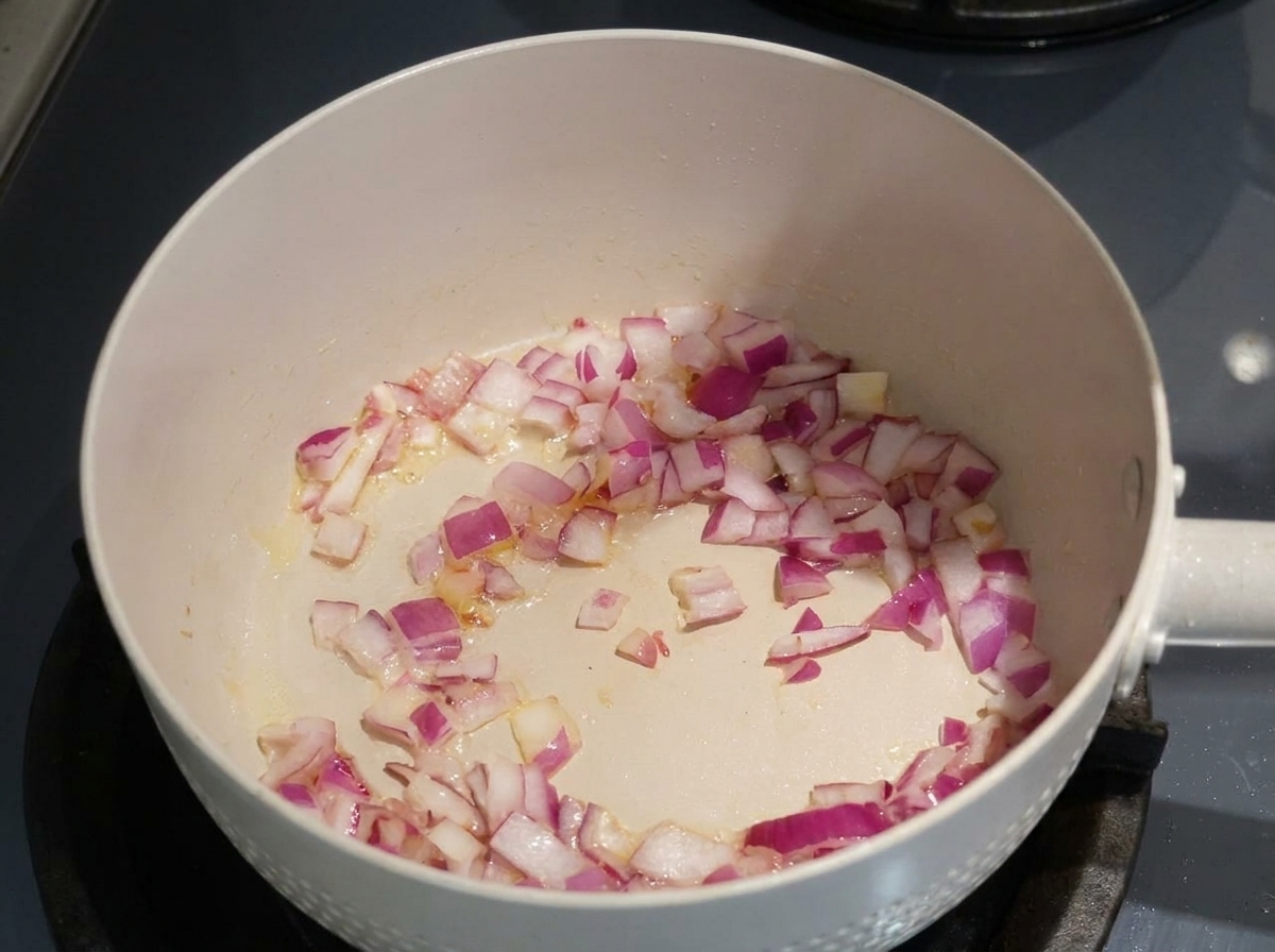 Gehackte rote Zwiebeln werden in einer Pfanne glasig gedünstet.