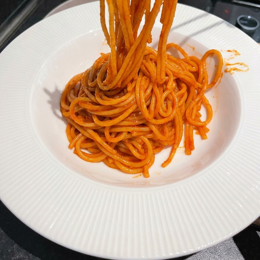 Spaghetti werden mit Stäbchen in einer Schüssel eingedreht.