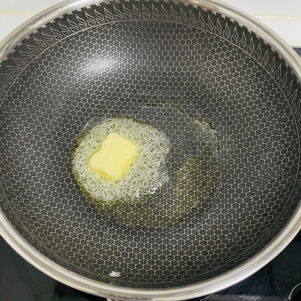 Ein Stück Butter schmilzt und schäumt in der Mitte eines großen Woks.
