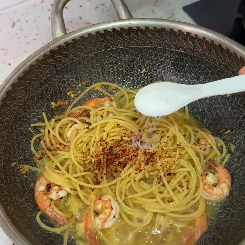 Salz wird mit einem Löffel über die Spaghetti im Wok gestreut.
