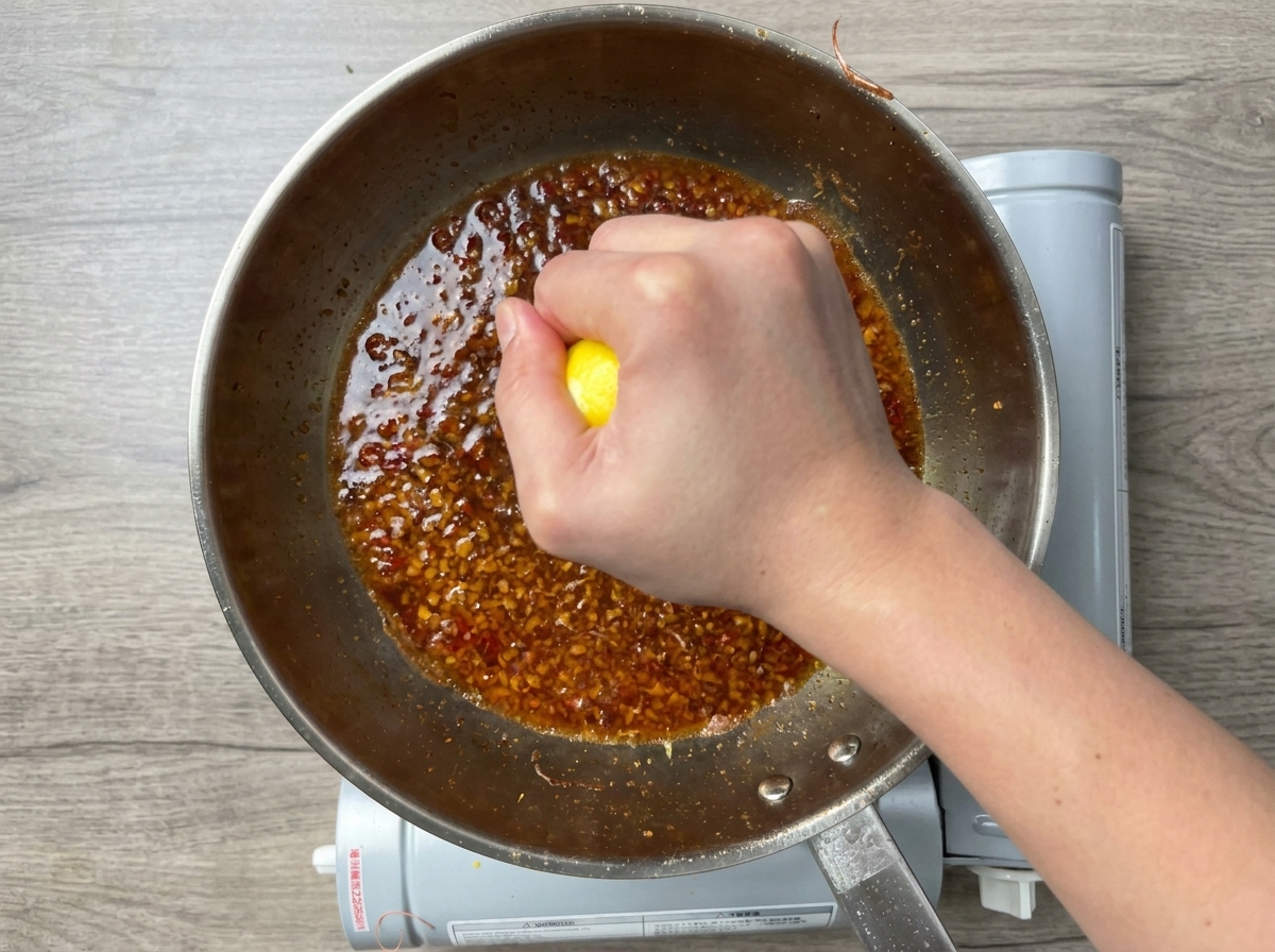 Eine Hand presst eine Zitrone in die Pfanne.