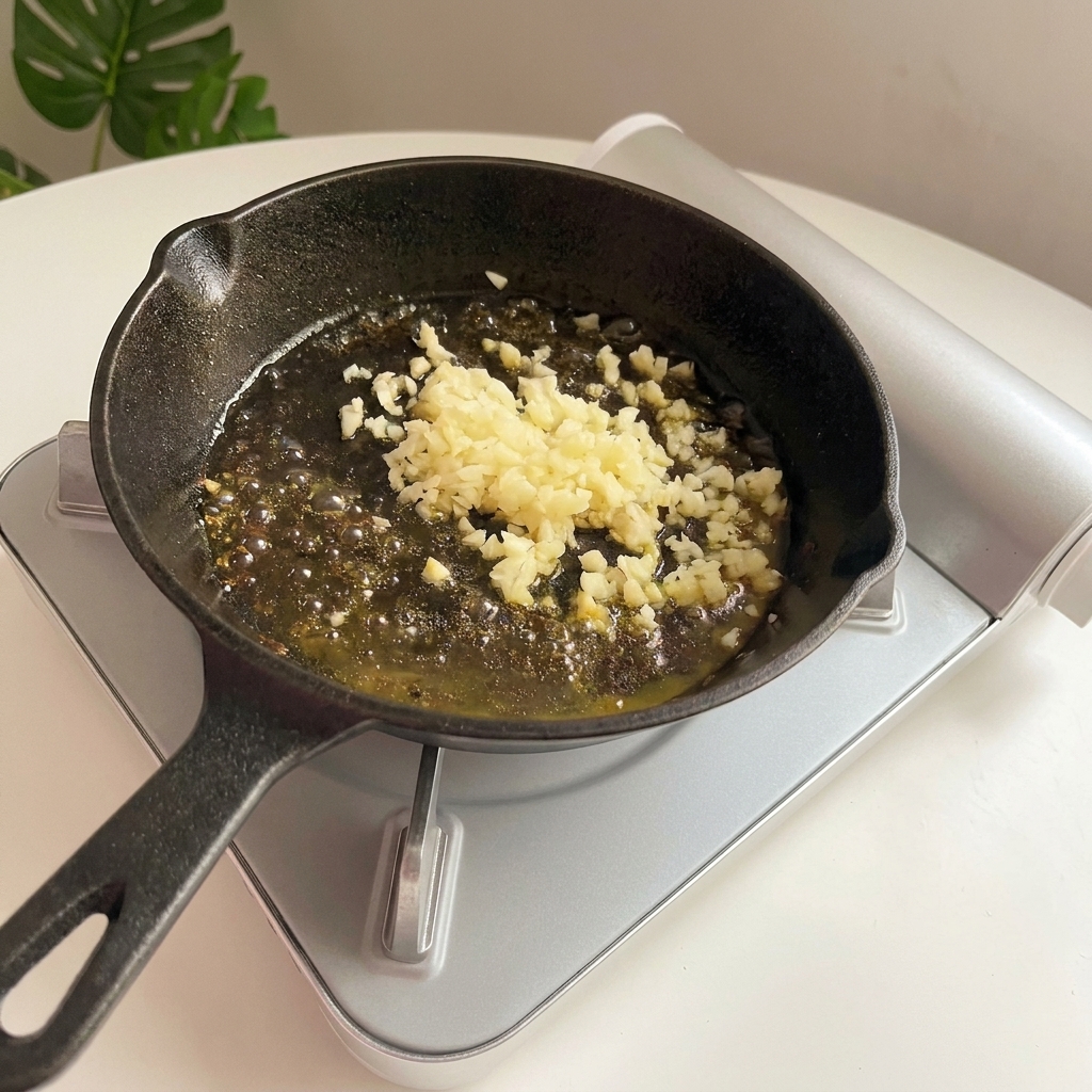 Fein gehackter Knoblauch brutzelt goldbraun in geschmolzener Butter in der Pfanne.