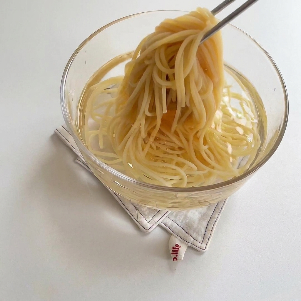 Gekochte Spaghetti werden in eine Glasschüssel mit kaltem Wasser gegeben.