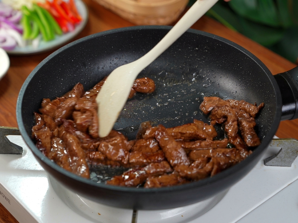 Marinierte Rindfleischstreifen werden in einer heißen Pfanne mit einem Pfannenwender gebraten.