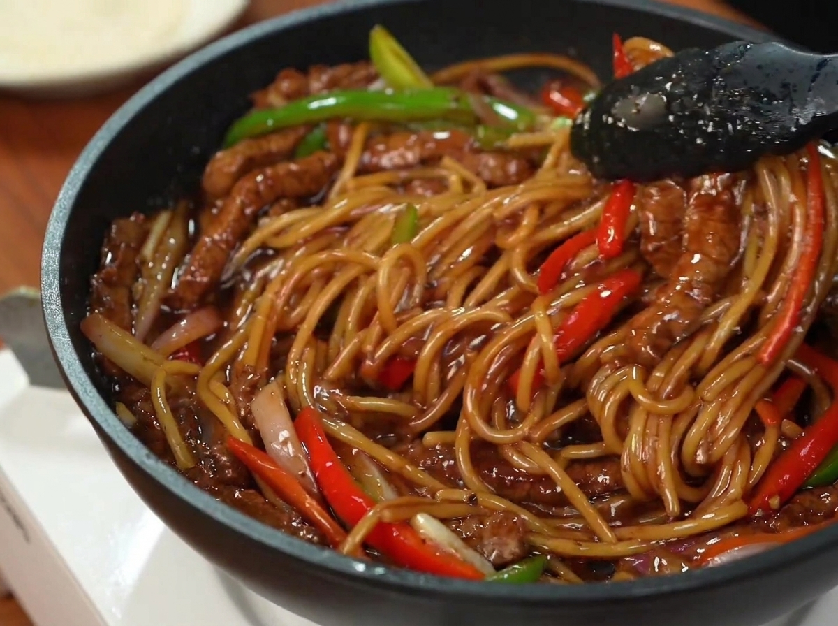 Ein fertiger Teller mit Pfeffer-Rindfleisch-Spaghetti, bestreut mit frischer Petersilie.